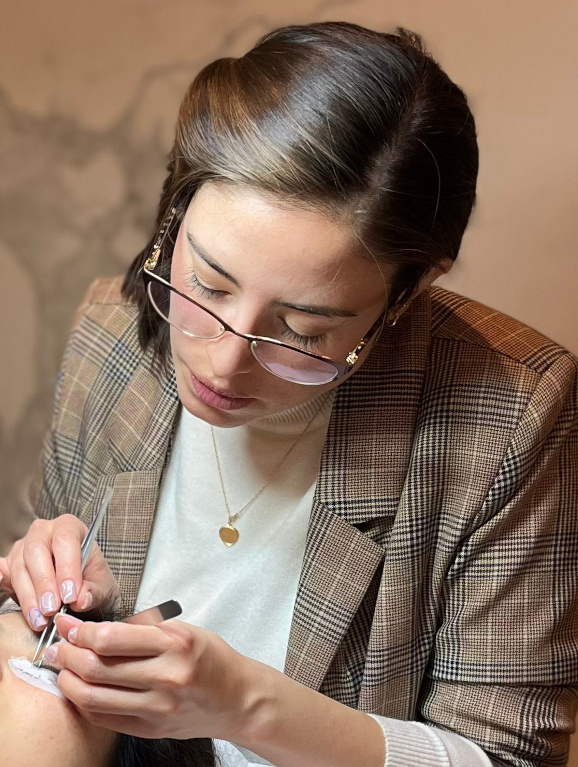 Skilled lash artist meticulously applies lash extensions in a well-equipped beauty studio